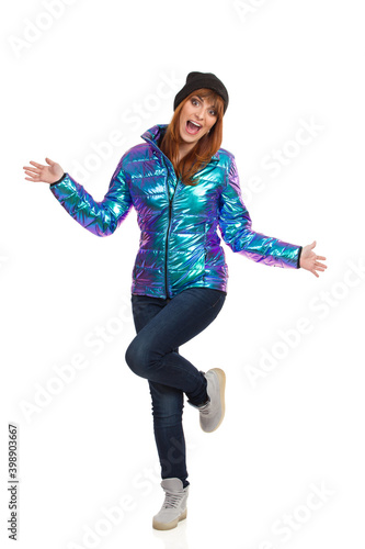 Happy Young Woman In Winter Clothes Is Standing On One Leg And Shouting.