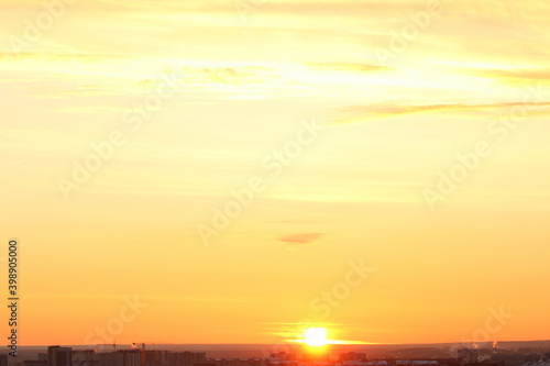 Sun below the horizon and clouds in the fiery dramatic orange sky at sunset or dawn backlit by the sun. Place for text and design