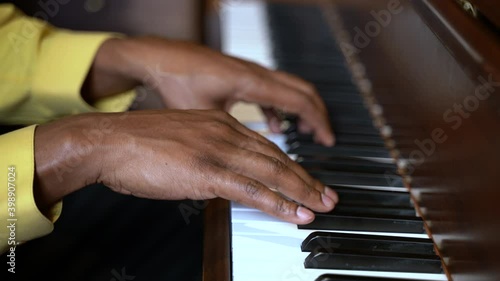 Closeup of black man hands playing brown piano