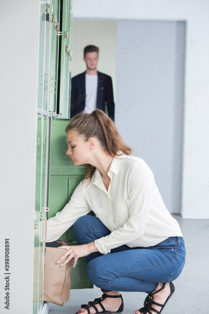 female student opening locker at university female student opening locker at university