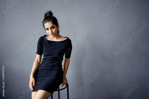 sexy woman in black dress sitting on bar stool indoors model hairstyle