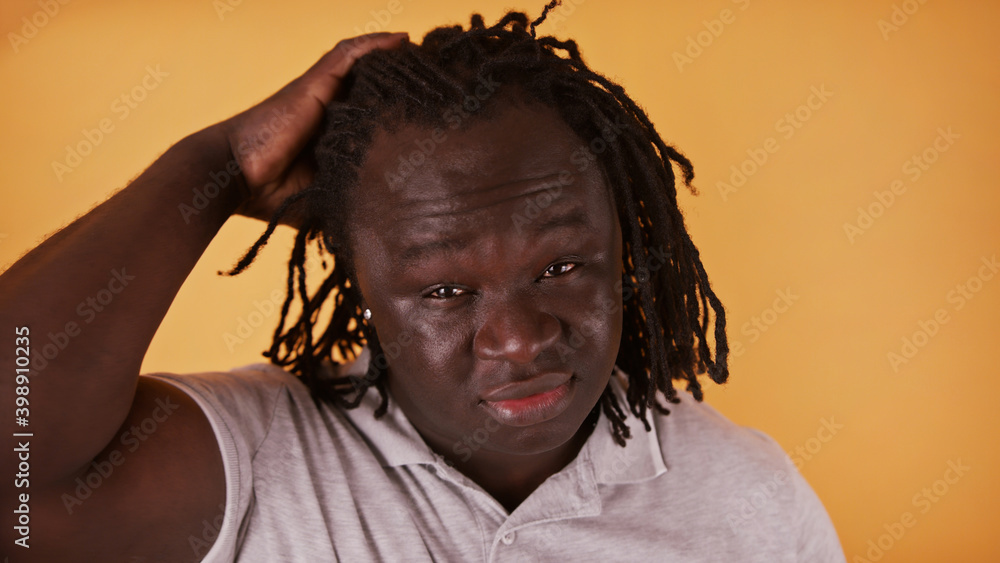 Portrait of young african american black man stroking his braided hair isolated over orange background. High quality photo Portrait of young african american black man stroking his braided hair isolated over orange background. High quality photo