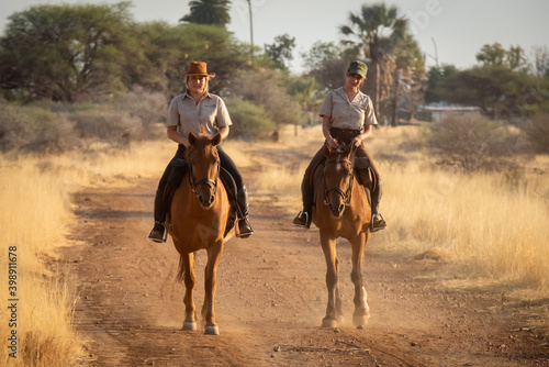 Blonde and brunette ride horses along track