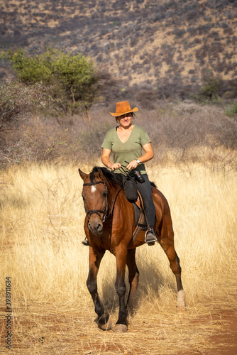 Blonde horsewoman rides towards camera in savannah © Nick Dale