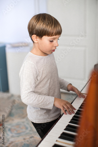 Happy boy plays the piano. Soft focus.
