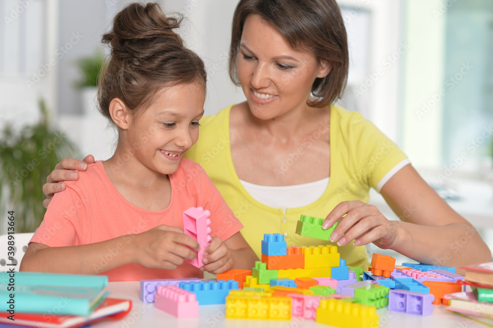 Girl and her mother playing with blocks at home Girl and her mother playing with blocks at home