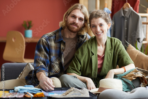 Portrait of young happy couple sitting on sofa together and smiling at camera at home
