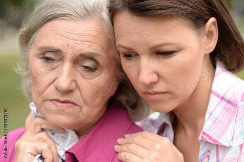 Close up portrait of sad senior woman with adult daughter
