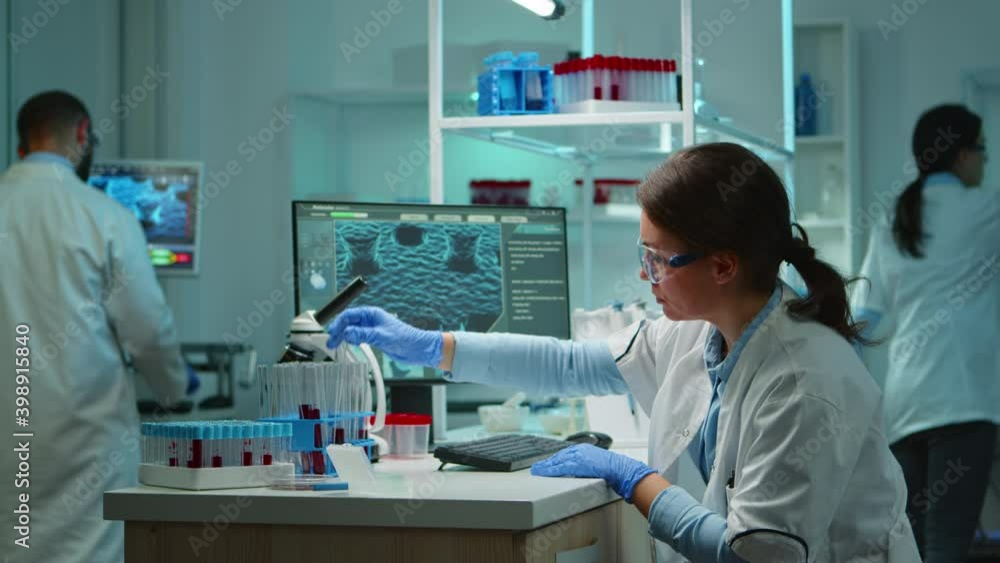 Scientist nurse typing on pc late at night sitting in scientific equipped laboratory. Medical stuff examining vaccine evolution using high tech for researching treatment against covid19 virus Scientist nurse typing on pc late at night sitting in scientific equipped laboratory. Medical stuff examining vaccine evolution using high tech for researching treatment against covid19 virus