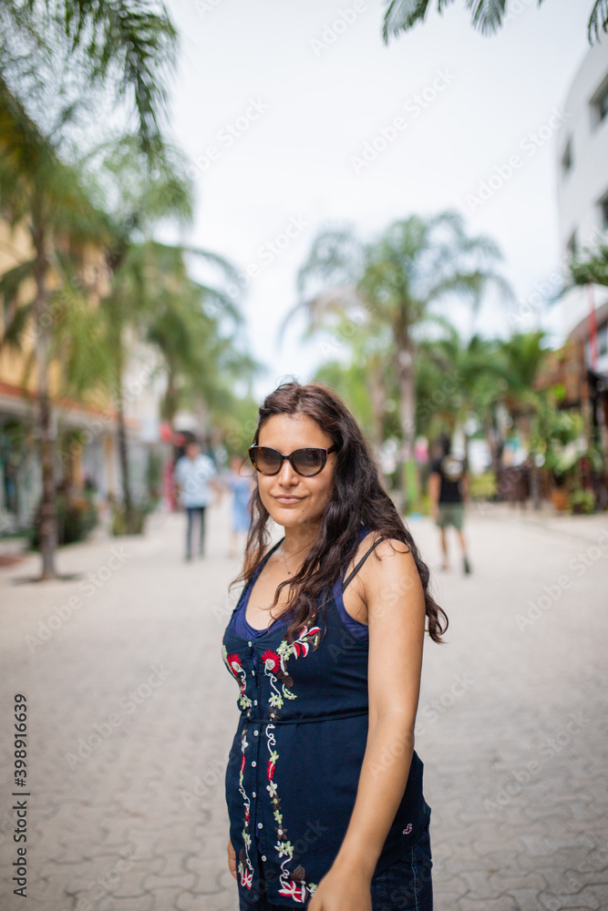 Beautiful woman wearing a dress standing in a tropical street