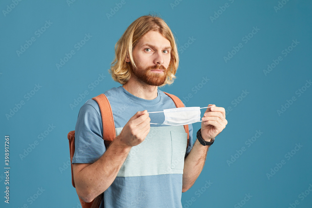 Portrait of young man wearing protective mask looking at camera isolated on blue background Portrait of young man wearing protective mask looking at camera isolated on blue background