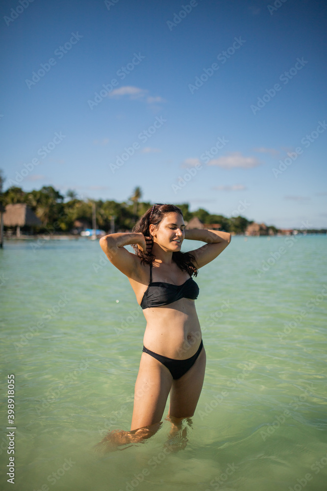 Beautiful joyful woman standing in water on the beach