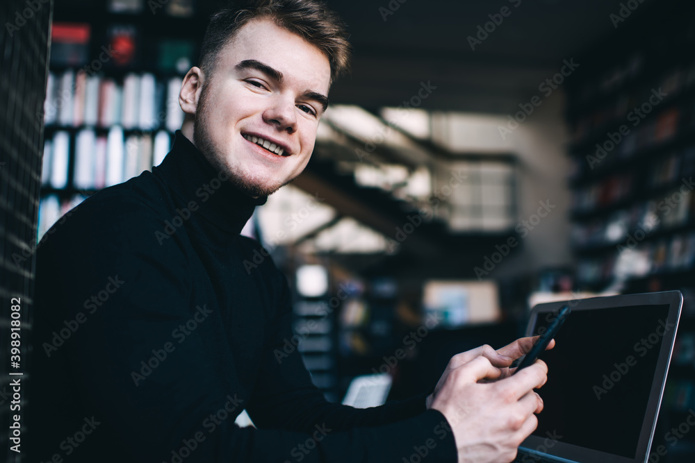 Cheerful young man using smartphone while resting Cheerful young man using smartphone while resting