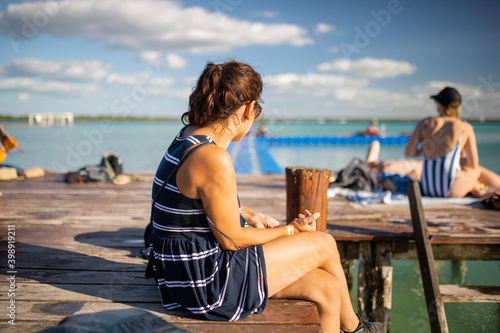 Beautiful woman sitting on the dock in the beach