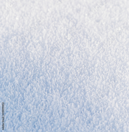 Snow, the texture of the surface of white snow with large crystals, illuminated by the oblique rays of the winter sun, background. © Alexander