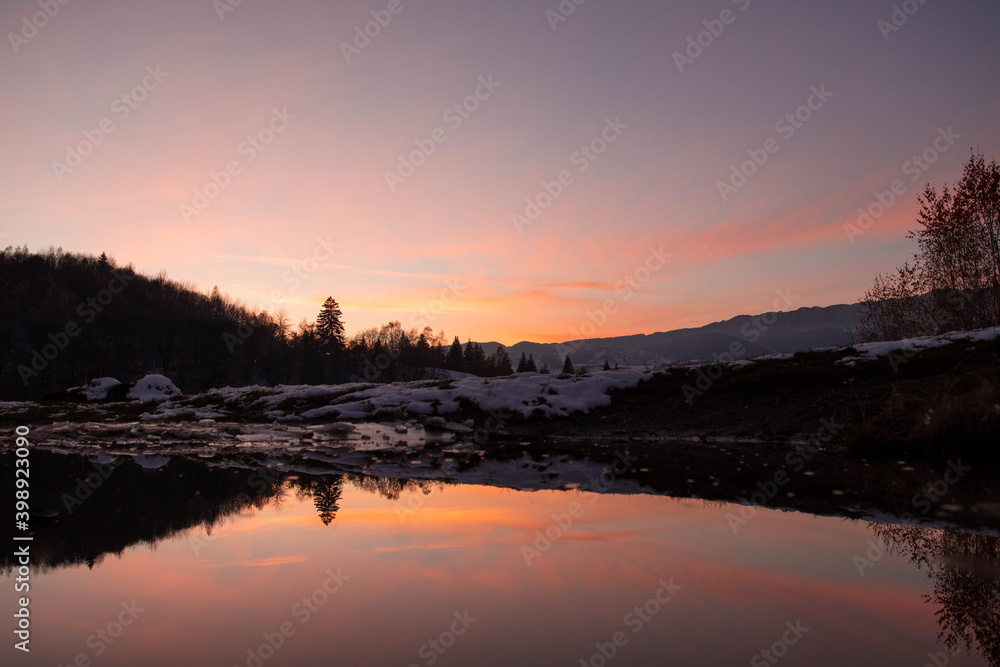 Amazing mountain sunset with reflection in the lake in winter