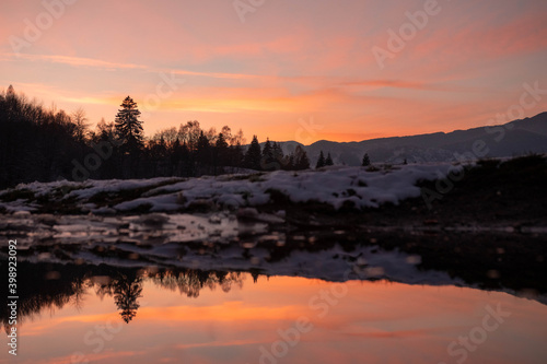 Amazing mountain sunset with reflection in the lake in winter