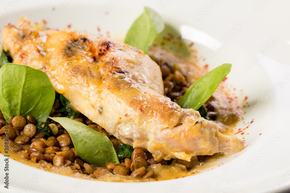 Stewed rabbit leg with lentils on a large round plate Stewed rabbit leg with lentils on a large round plate