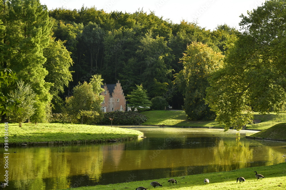 Obraz premium L'un des étangs avec au fond la Maison Espagnole autrefois moulin à eau actuellement un restaurant dans l'ombre des arbres majestueux au parc de Tervuren à l'est de Bruxelles