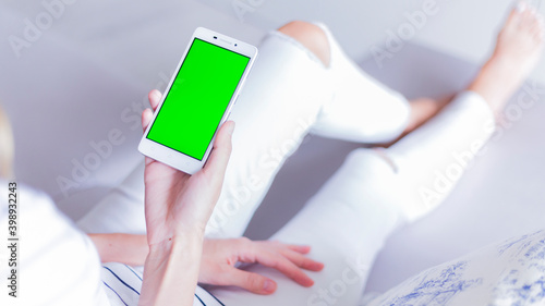 woman is relaxing on comfortable couch and using smartphone at home