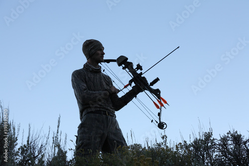 bow hunter holding bow and arrow at dusk