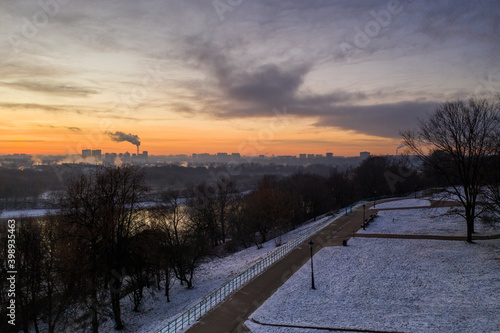 panoramic view of the park in the city on the river bank with old buildings at sunrise in winter filmed from a drone