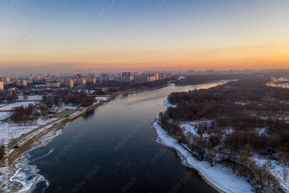panoramic view of the park in the city on the river bank with old buildings at sunrise in winter filmed from a drone