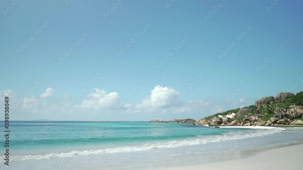 Exotic beach by the ocean with rolling waves on the sandy shore and blue sky. Exotic beach by the ocean with rolling waves on the sandy shore and blue sky.