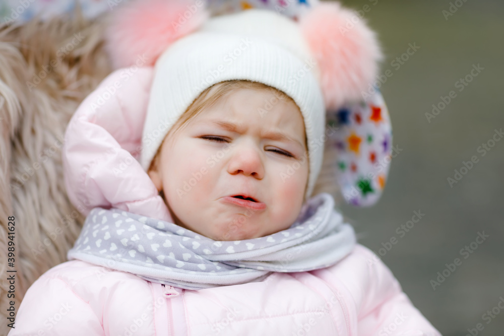 Sad crying hungry baby girl sitting in the pram or stroller on cold autumn, winter or spring day. Weeping child in warm clothes, fashion stylish baby coat and hat. Snow falling down Sad crying hungry baby girl sitting in the pram or stroller on cold autumn, winter or spring day. Weeping child in warm clothes, fashion stylish baby coat and hat. Snow falling down