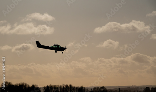 a light aircraft on landing approac silhoutted against the early evening sky