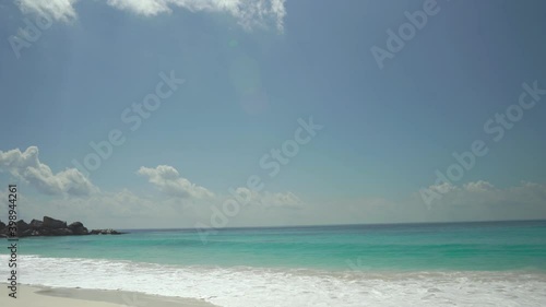 Exotic beach by the ocean with rolling waves on the sandy shore and blue sky