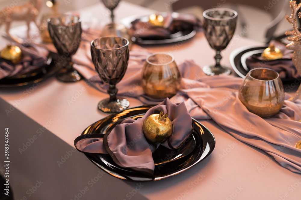 Close up of festive Christmas table setting with empty wine glasses and black plate with gold garnet Close up of festive Christmas table setting with empty wine glasses and black plate with gold garnet