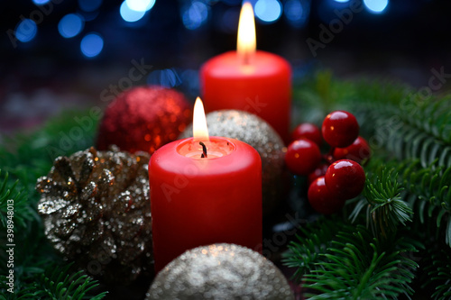 Lighted red candles surrounded by holiday decorations.
