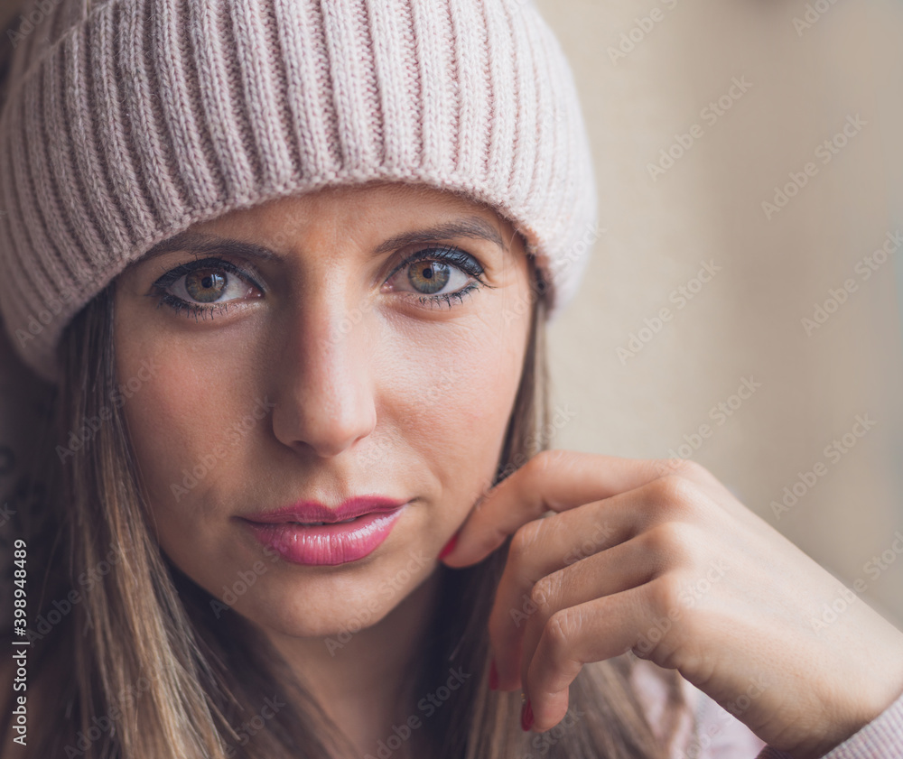 retrato en primer plano de mujer joven de ojos verdes y gorro de lana, sobre un fondo neutro y espacio libre en la derecha. retrato en primer plano de mujer joven de ojos verdes y gorro de lana, sobre un fondo neutro y espacio libre en la derecha.