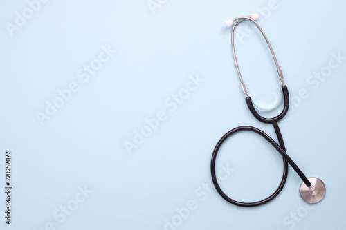 Blank medical clipboard with stethoscope on blue background.