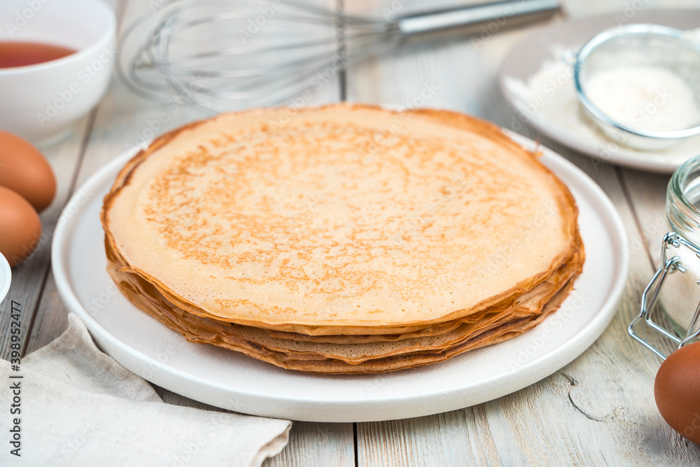 Cooking background with pancakes and ingredients on a light table. Side view. The concept of cooking, recipes, Mardi Gras. Cooking background with pancakes and ingredients on a light table. Side view. The concept of cooking, recipes, Mardi Gras.