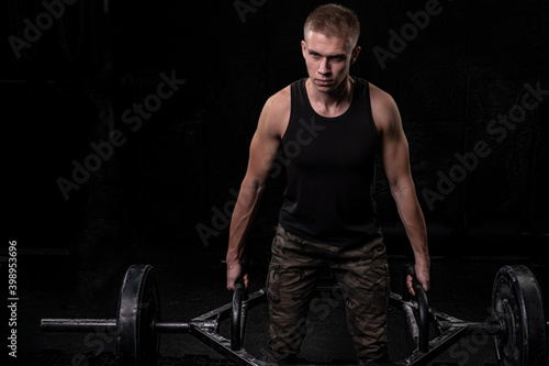 a strong guy with pumped up arms holds a barbell in his hands