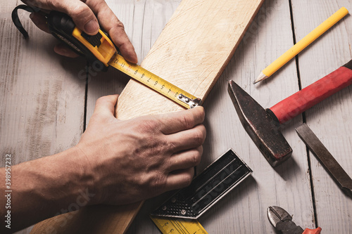 Carpenter measures the workpiece with a tape measure, tools, top view