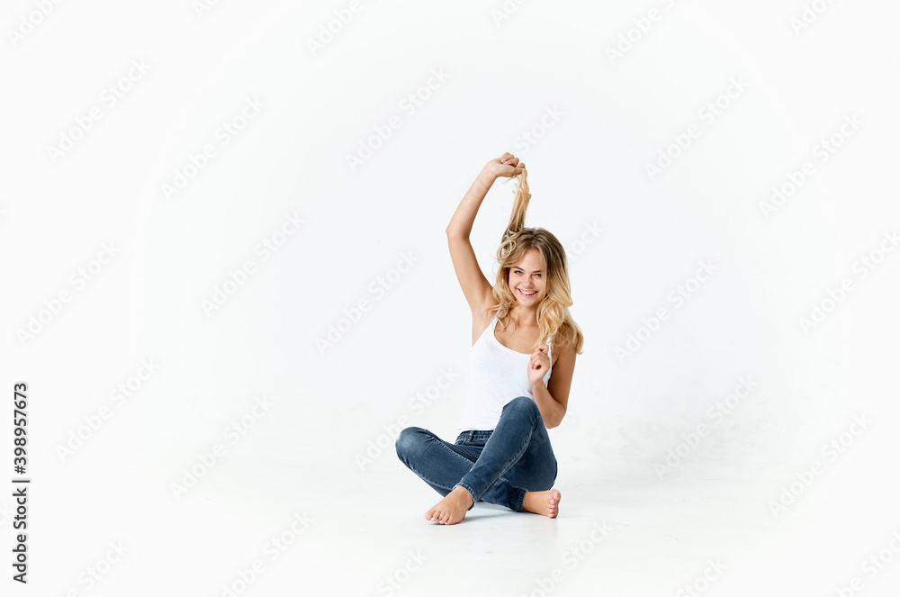 pretty lady in jeans and a white t-shirt sits on the floor in a bright roompretty lady in jeans and a white t-shirt  