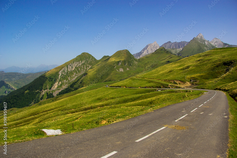 Mountain road surrounded by green meadows through the French Pyrenees