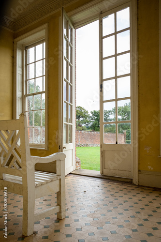 Wooden cream bench in Victorian summer house. Large windows, floor to ceiling let in so much light. Beautiful view of walled garden.