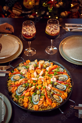 Spanish dinner table with assortment of dishes. paella, octopus, whole fish, sangría and wine. Dressed for christmas