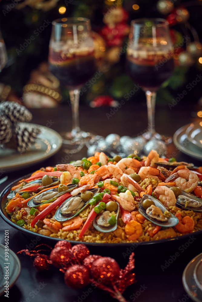Spanish dinner table with assortment of dishes. paella, octopus, whole fish, sangría and wine. Dressed for christmas