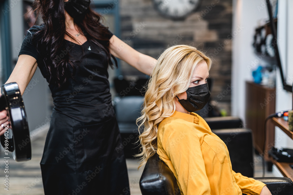 Beautiful hairstyle of middle-aged woman with protective face mask after dyeing hair in hair salon. Beautiful hairstyle of middle-aged woman with protective face mask after dyeing hair in hair salon.