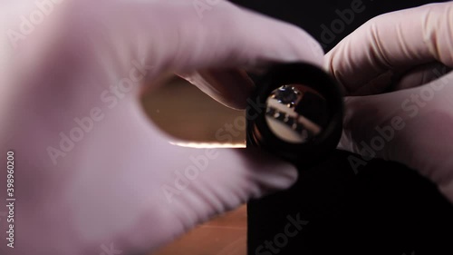 Goldsmith evaluates the gold ring using a close up magnifying glass and hands over cash. Pawnshop owner examining jewel with monocular loupe. Theme of business buying of precious metals and deal loan