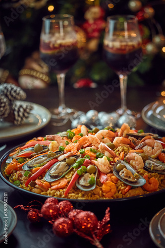 Spanish dinner table with assortment of dishes. paella  octopus  whole fish  sangr  a and wine. Dressed for christmas
