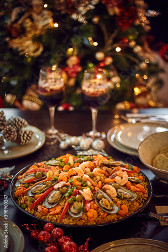 Spanish dinner table with assortment of dishes. paella, octopus, whole fish, sangría and wine. Dressed for christmas