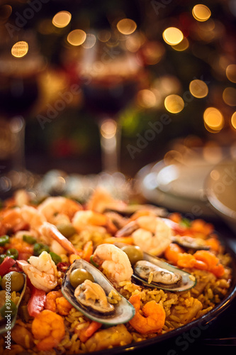 Spanish dinner table with assortment of dishes. paella, octopus, whole fish, sangría and wine. Dressed for christmas