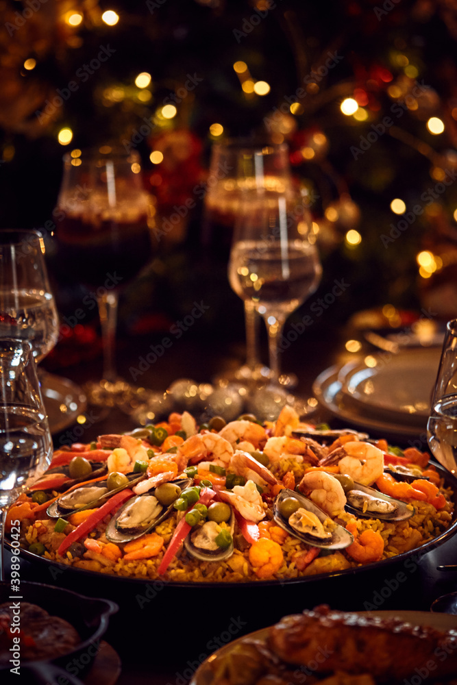 Spanish dinner table with assortment of dishes. paella, octopus, whole fish, sangría and wine. Dressed for christmas