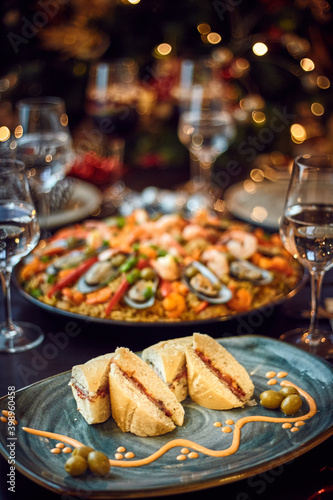 Spanish dinner table with assortment of dishes. paella, octopus, whole fish, sangría and wine. Dressed for christmas